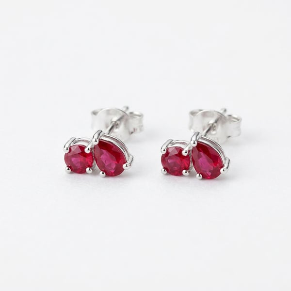 Studio photo of Mishael 925 sterling silver toi et moi ruby stud earrings on a white background.