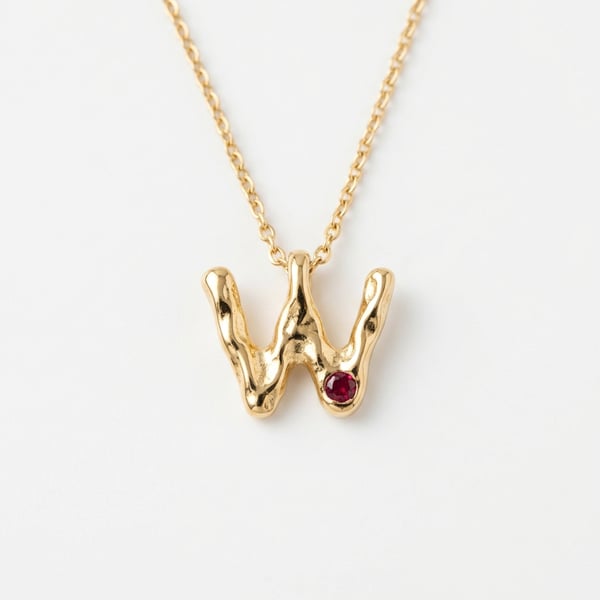 Organic molten 18K gold initial W pendant featuring a flush-set round ruby on a fine chain.