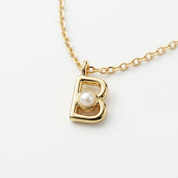 18K yellow gold letter B initial pendant with a small round pearl on a fine chain on a white background