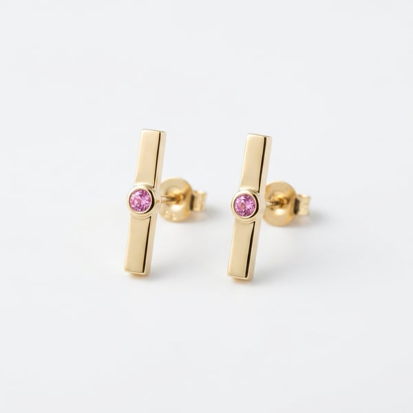 Pair of 18K gold geometric bar earrings with bezel-set pink sapphires on a plain white background.