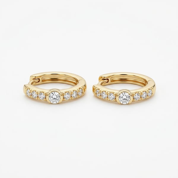 Pair of Zakirah 18K gold huggie hoop earrings with flush-set center diamonds and pavé accent diamonds on a white background.