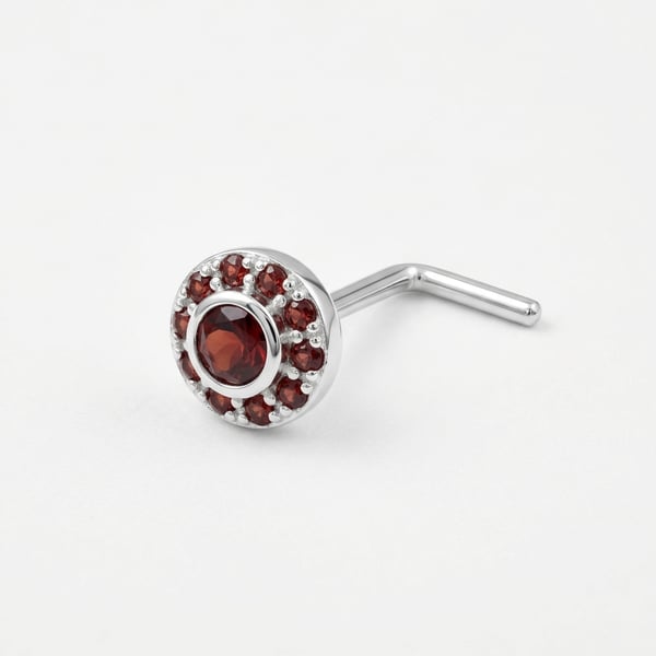 Macro studio photo of the Hessah sterling silver nose stud featuring a central round garnet with a pavé garnet halo on a white background.