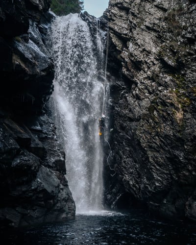 Guide abseils down waterfall at falls of bruar canyon in scotland uk