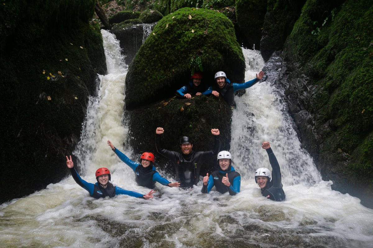 Small group enjoy canyoning in Scotland, splashing in a beautiful wild swimming pool in Dollar Glen canyon, Clackmannanshire, Scotland