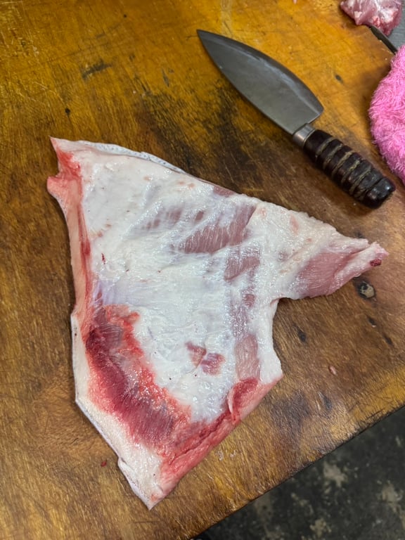 Actual pork jowl, triangular shape with white fat layer and dark lean meat inside