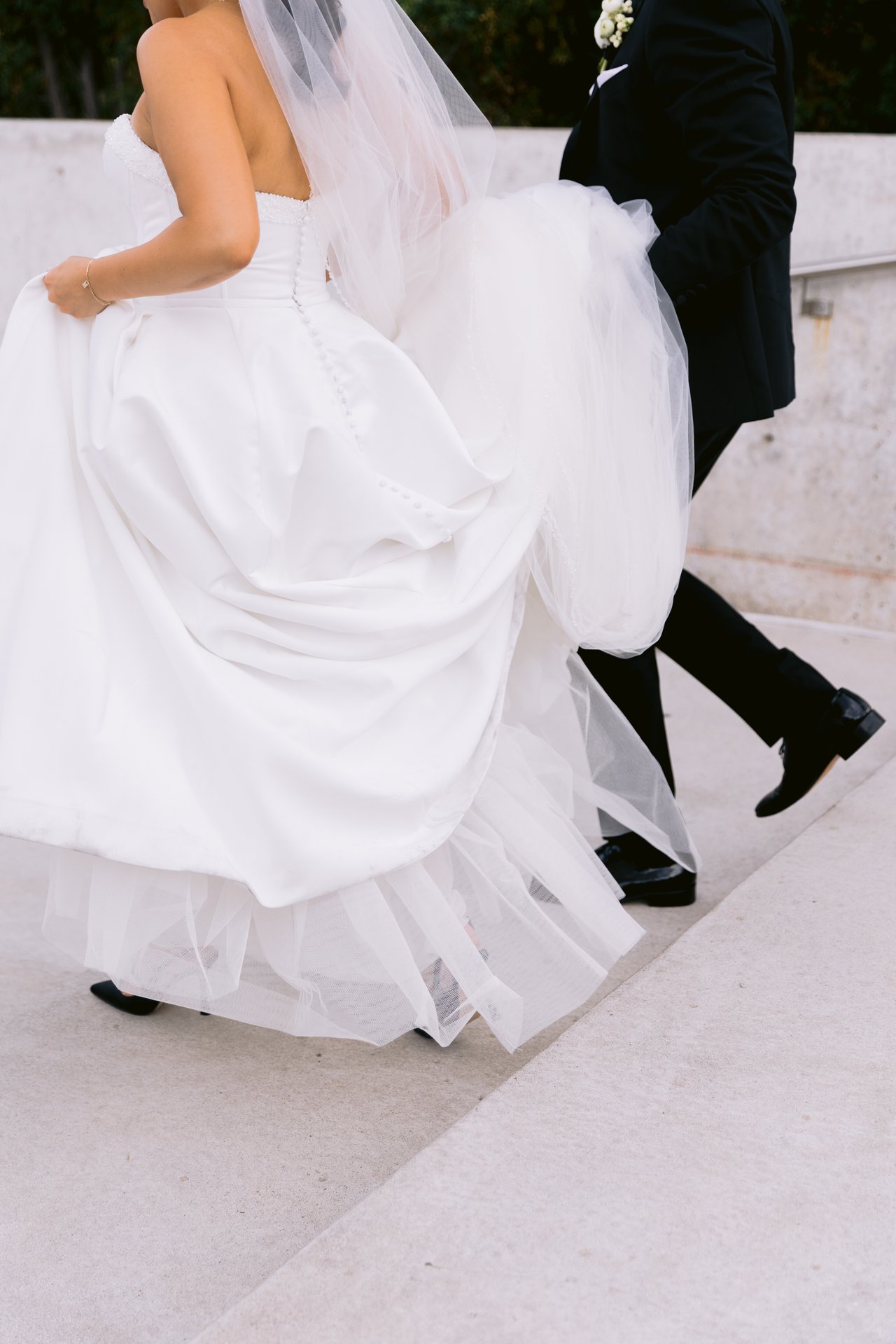 Groom helping the bride hold her dress as they walk together, close-up of the dress, Aga Khan Museum