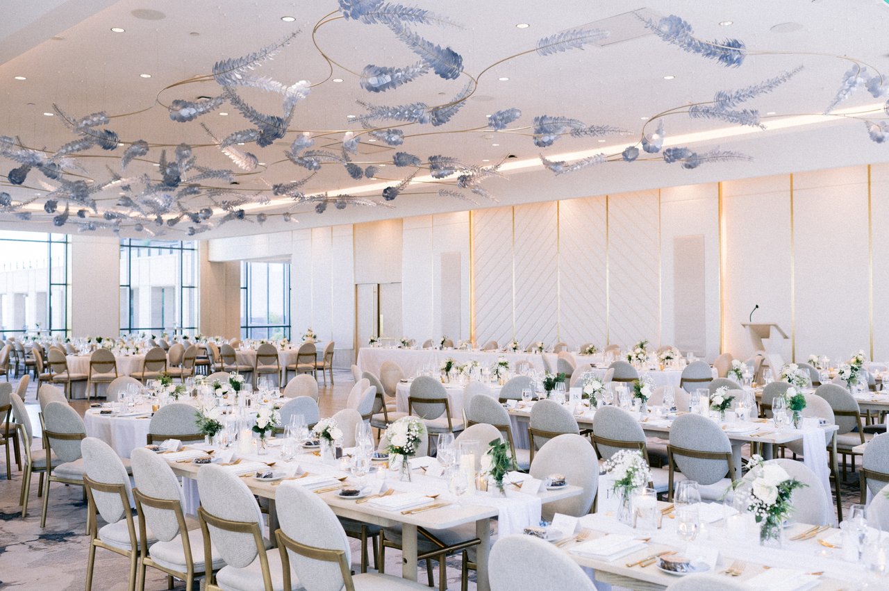 Pearle Hotel & Spa wedding reception set before guests arrive — sculptural silver ceiling installation, round tables with floral centerpieces, soft natural light