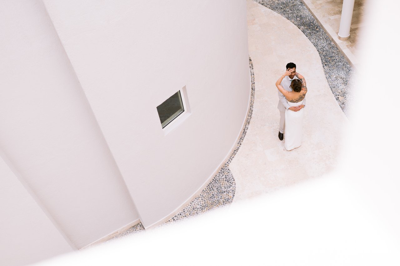 Iris and Hussain alone in the white resort architecture, from above