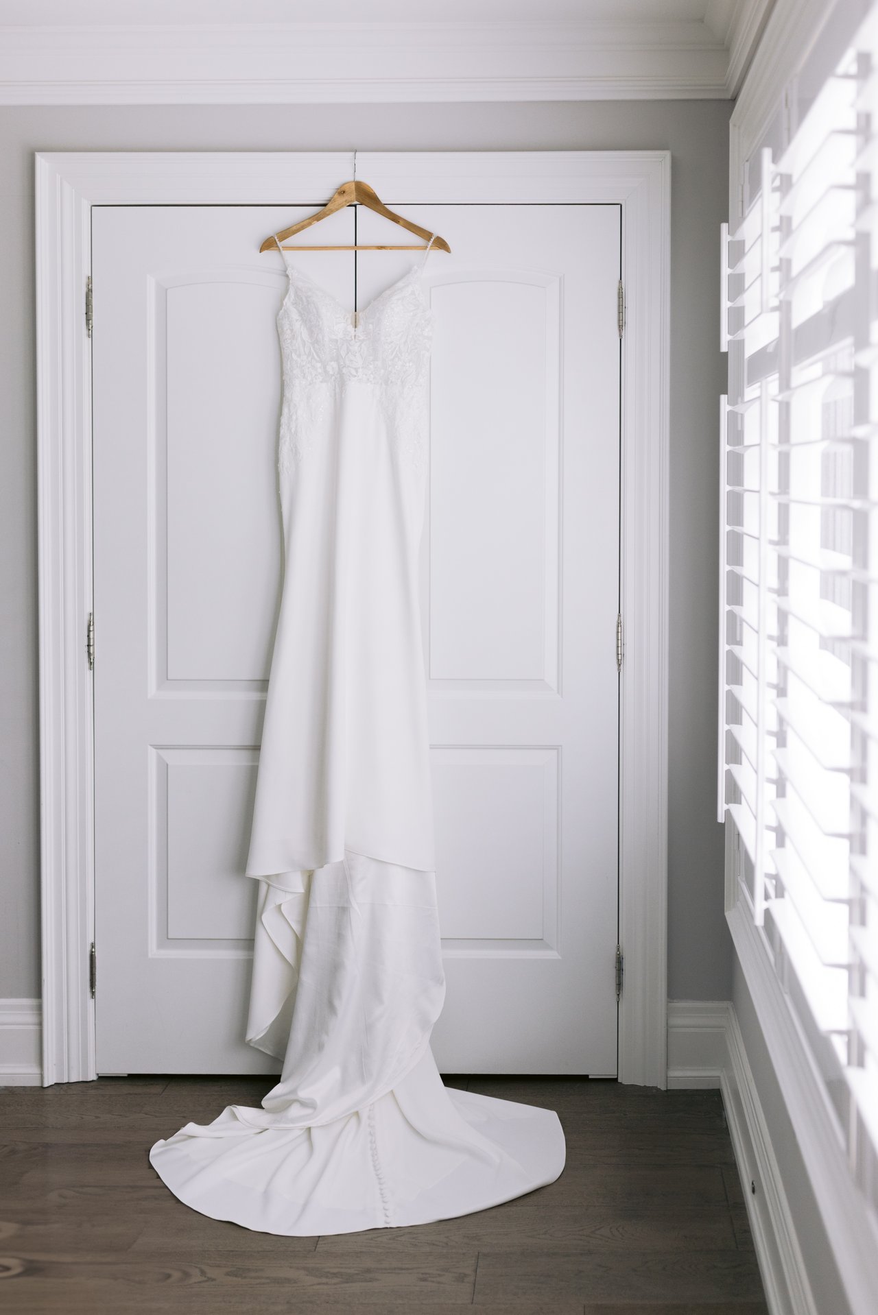 Midori's gown hanging full length against a white door