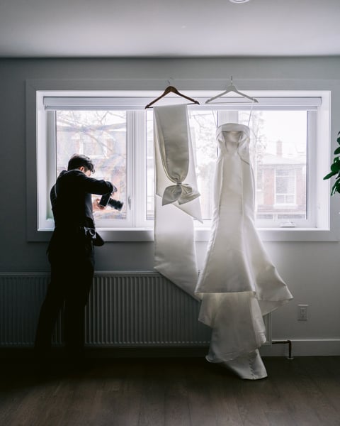 Forster photographing a wedding gown by a window