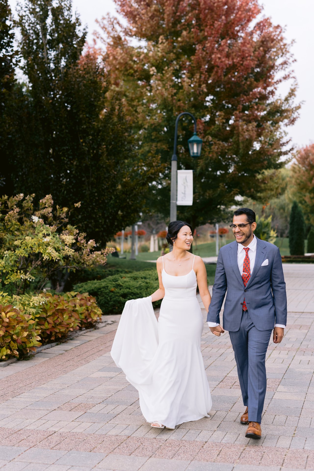 Vicky and Saurabh walking a tree-lined path in the autumn light