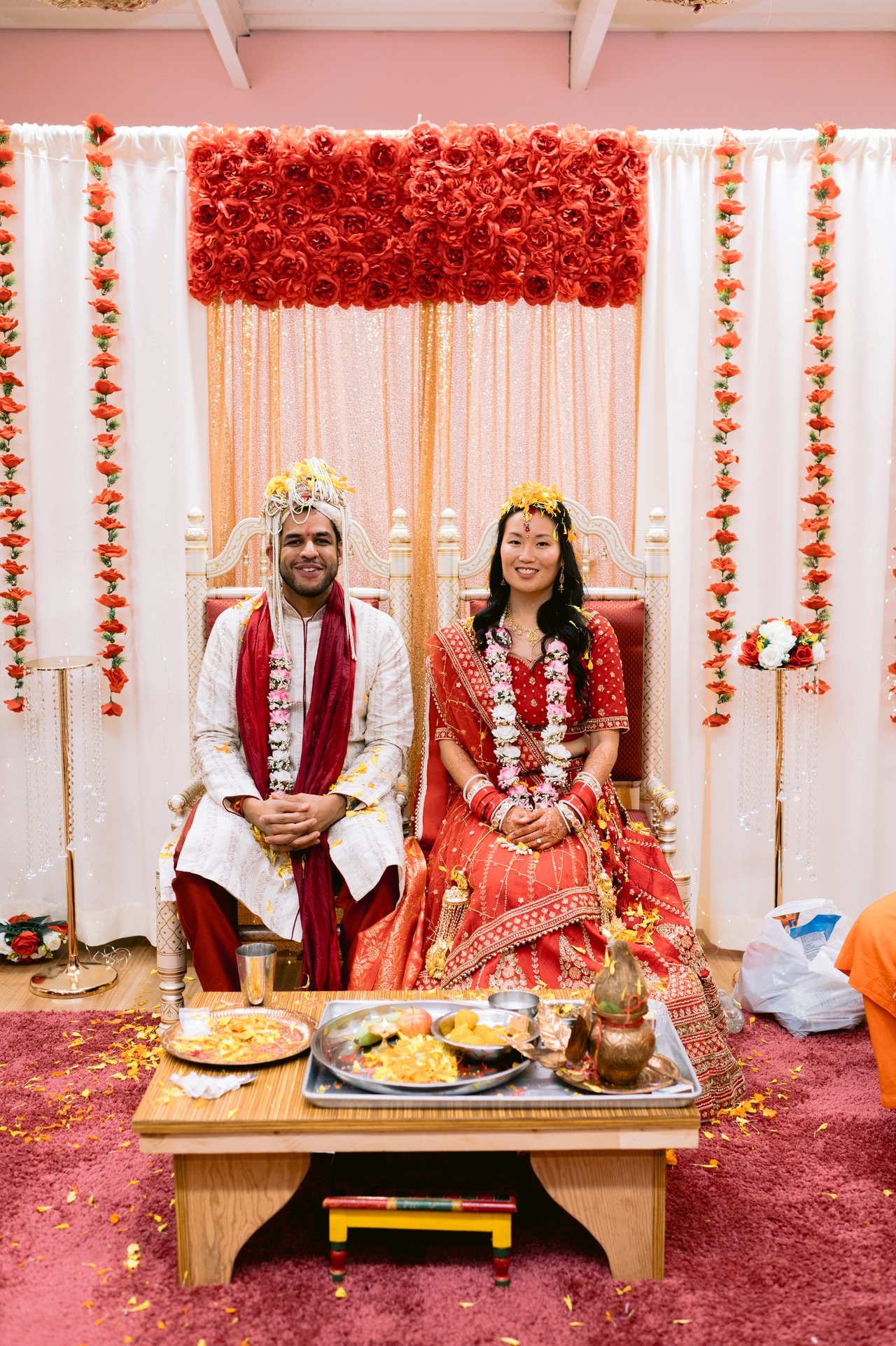 Vicky and Saurabh seated at the marigold-draped mandap