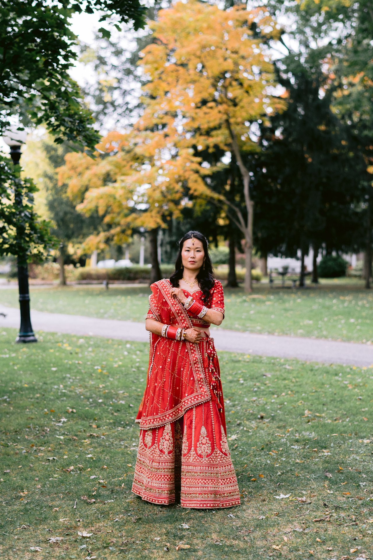 Vicky in her red lehenga among the fall trees