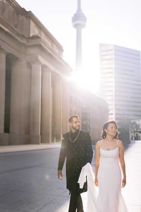 Vicky and Saurabh at the base of the CN Tower in golden-hour light