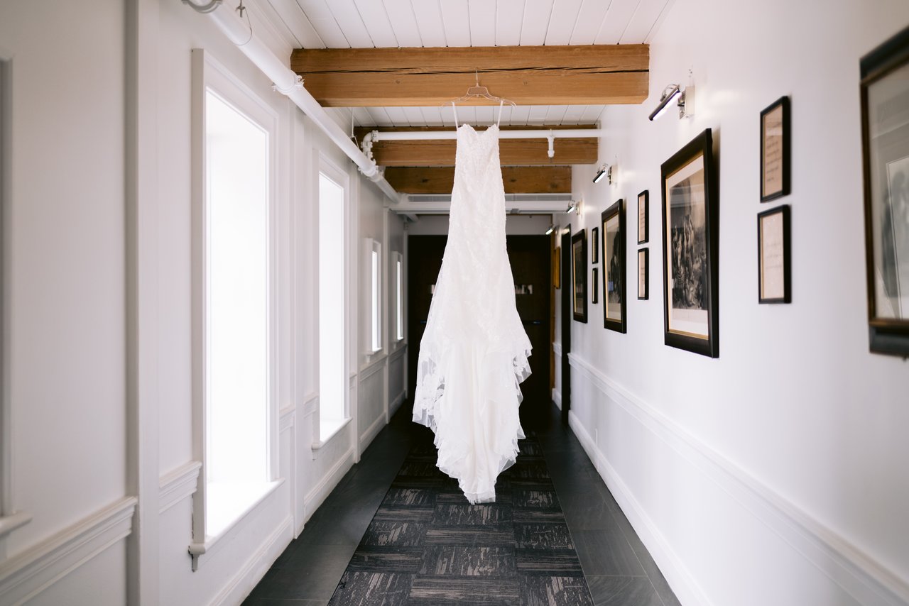 The dress hanging in the gallery hallway, framed art down the wall