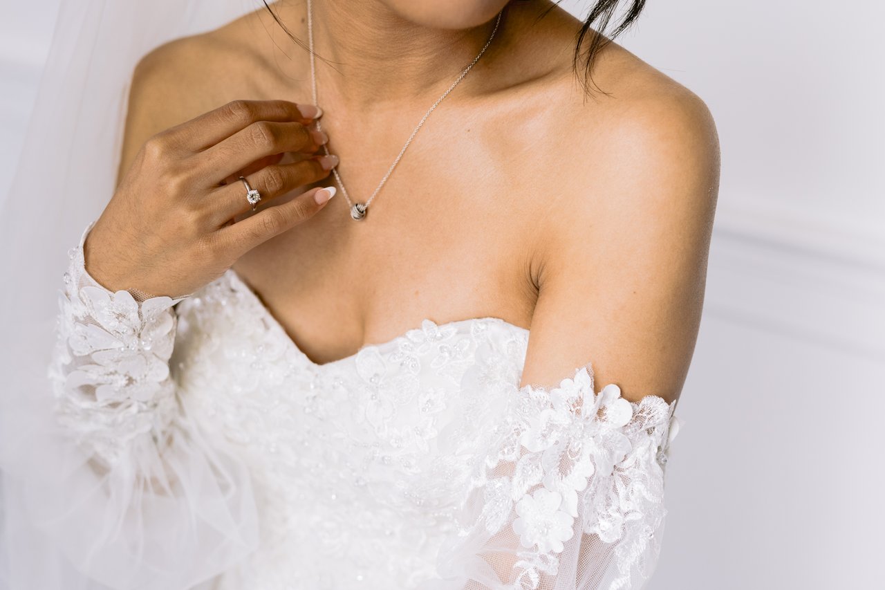 Her hands at the neckline, the sleeves off the shoulder