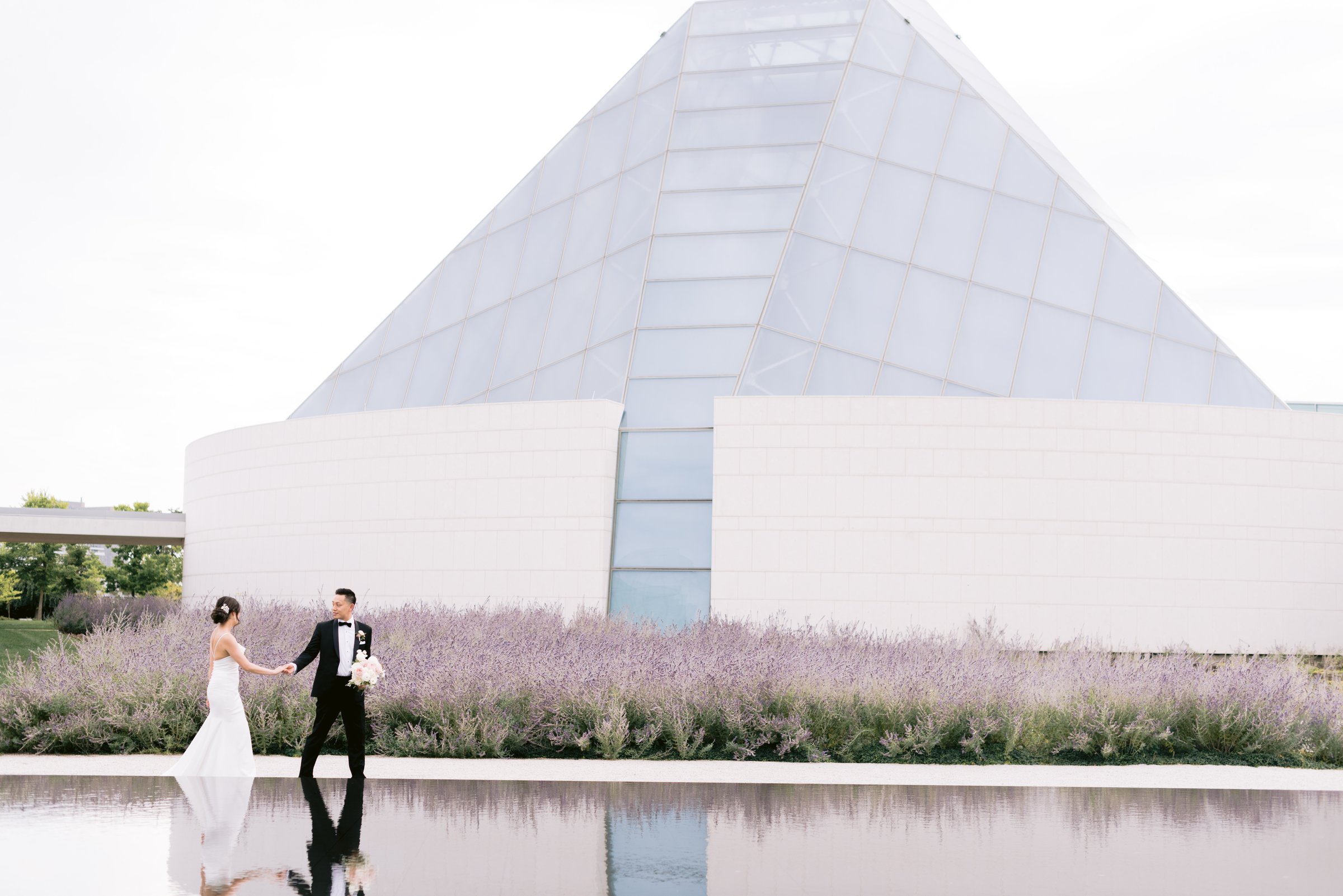 Katie and Harry small against the glass pyramid and lavender at the Aga Khan Museum