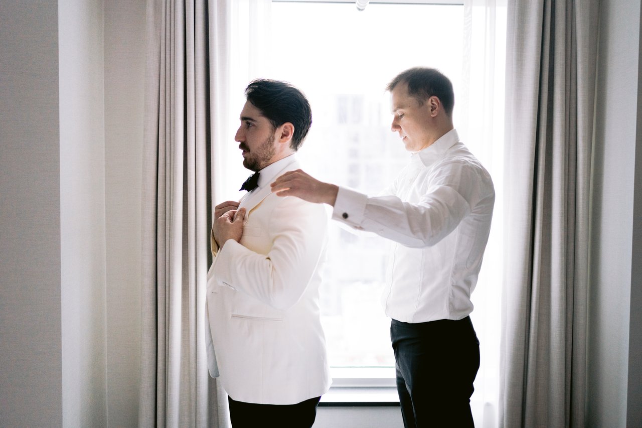 A groomsman helping Will dress