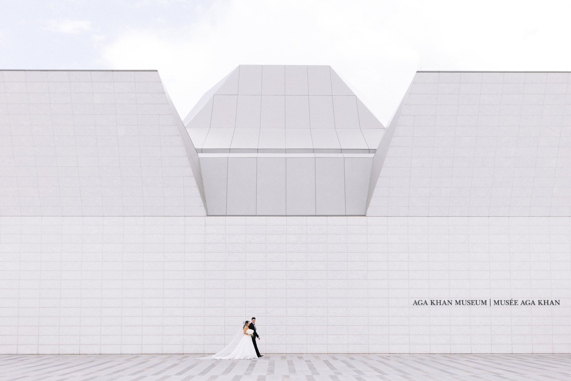 Susana and Jordan small against the white facade of the Aga Khan Museum