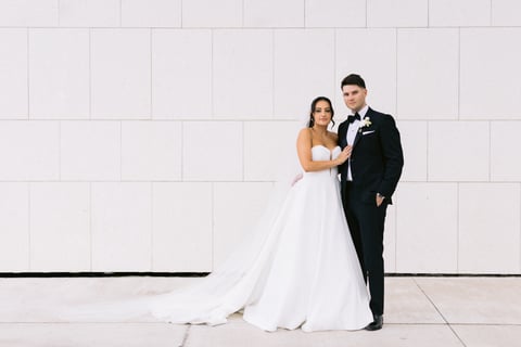 Susana and Jordan against the white wall of the Aga Khan Museum