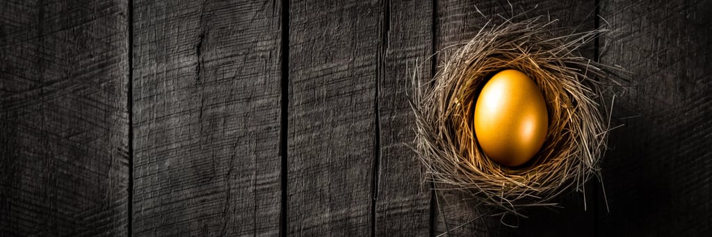 Gold egg in a nest made of sticks that is siting on a wooden floor made of old planks