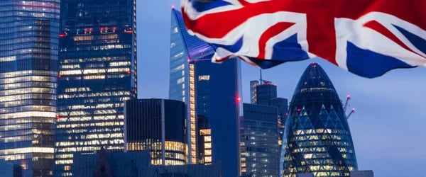 Image of United Kingdom flag with afternoon city lights in background