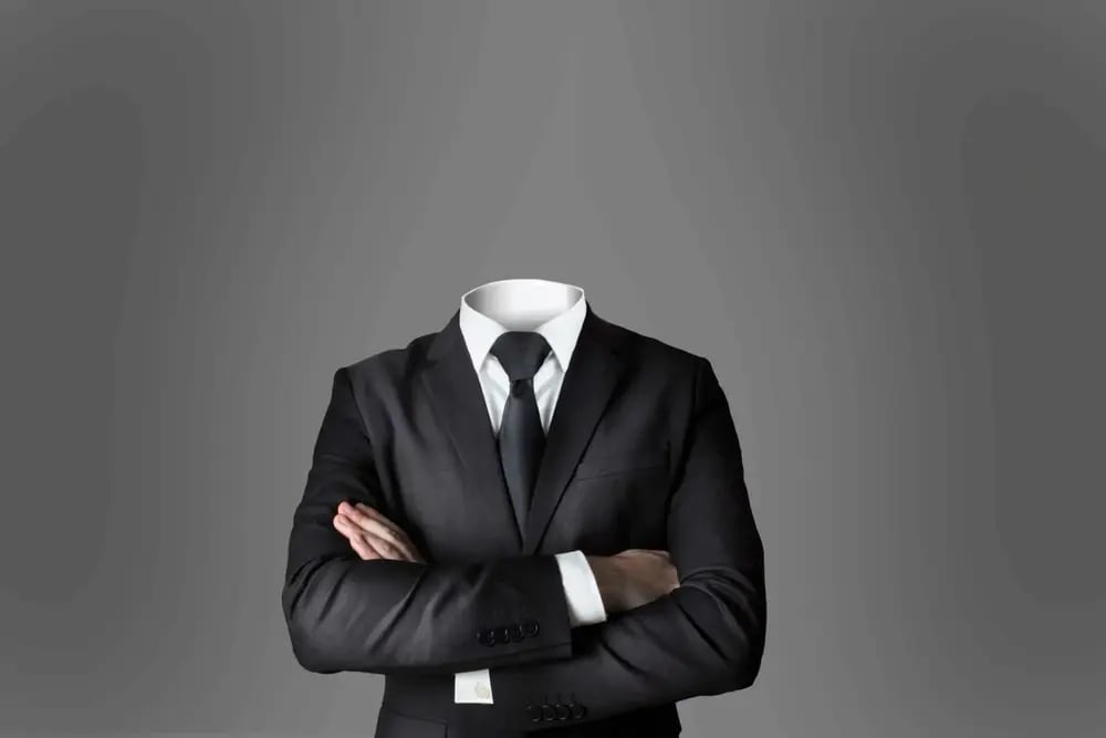 man wearing suit with no head with arms crossed with grey background
