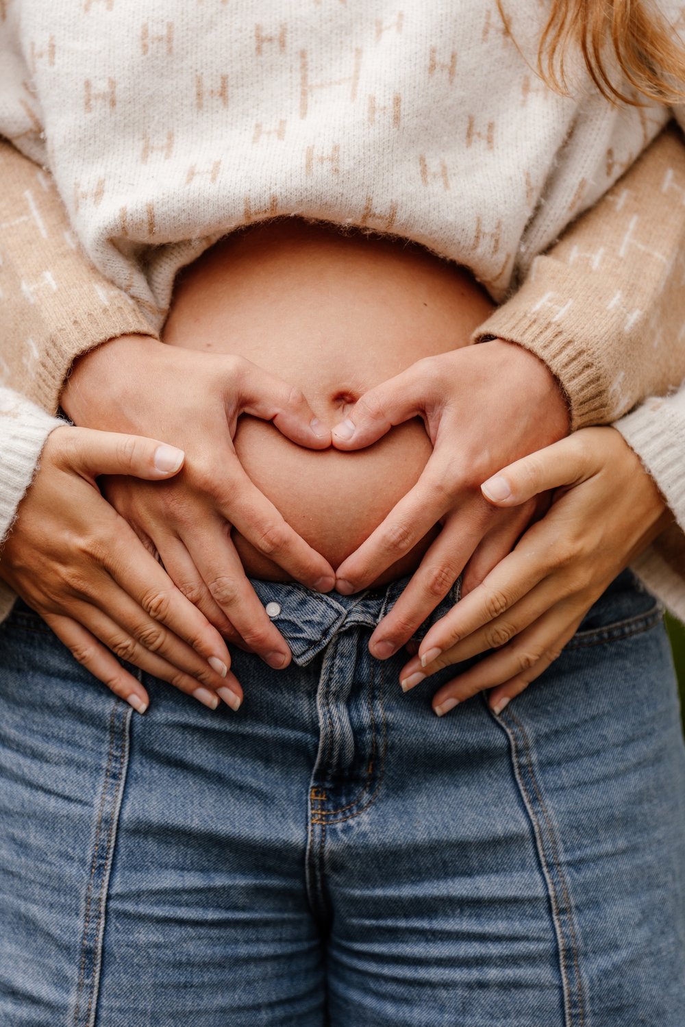 Gravid mage med to par hender formet som et hjerte