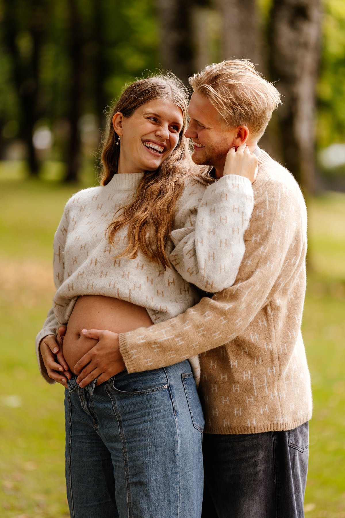 Gravid kvinne og partneren hennes ler sammen i en park