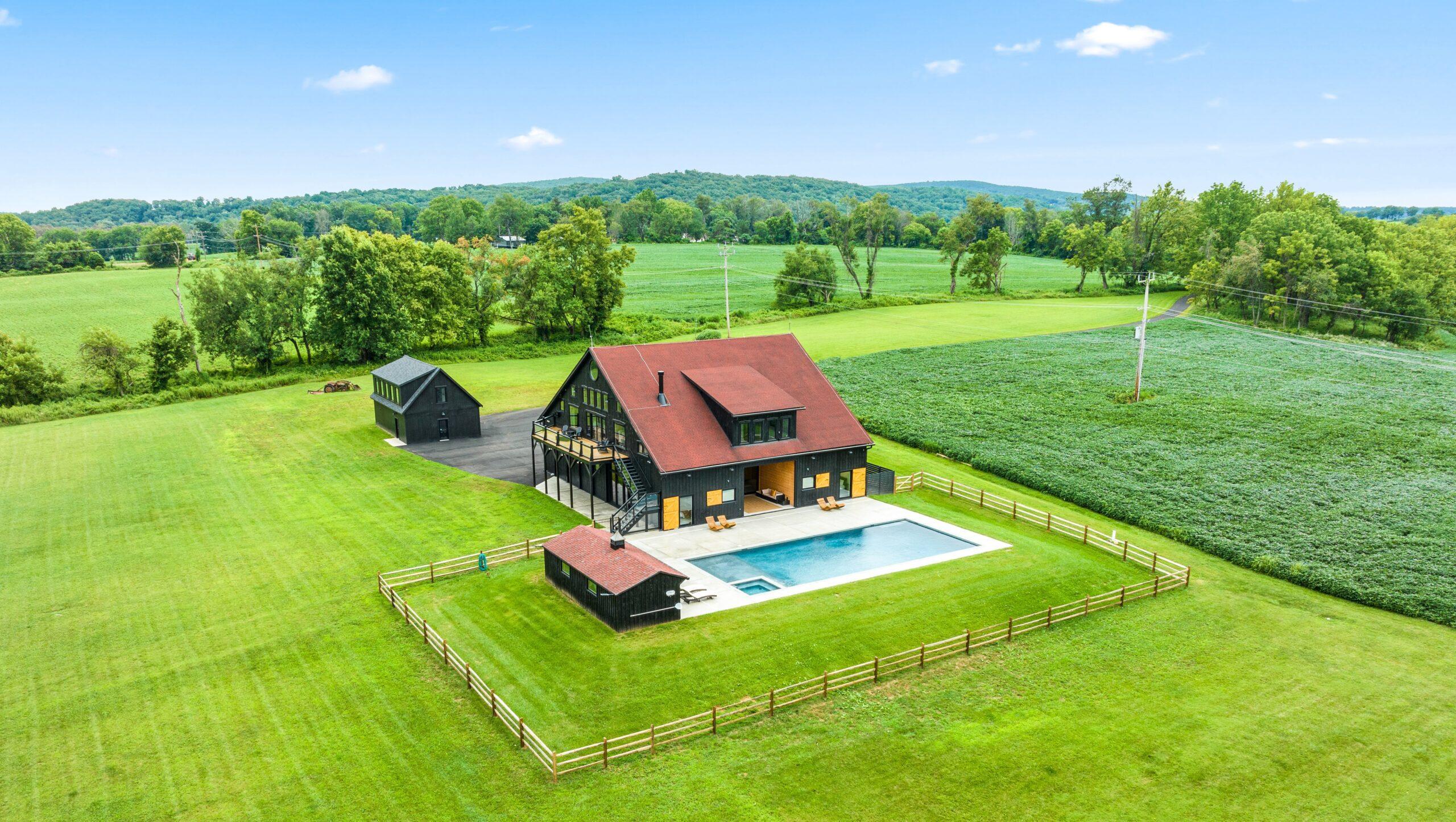 Aerial view of a home surrounded by open fields and wooded hills