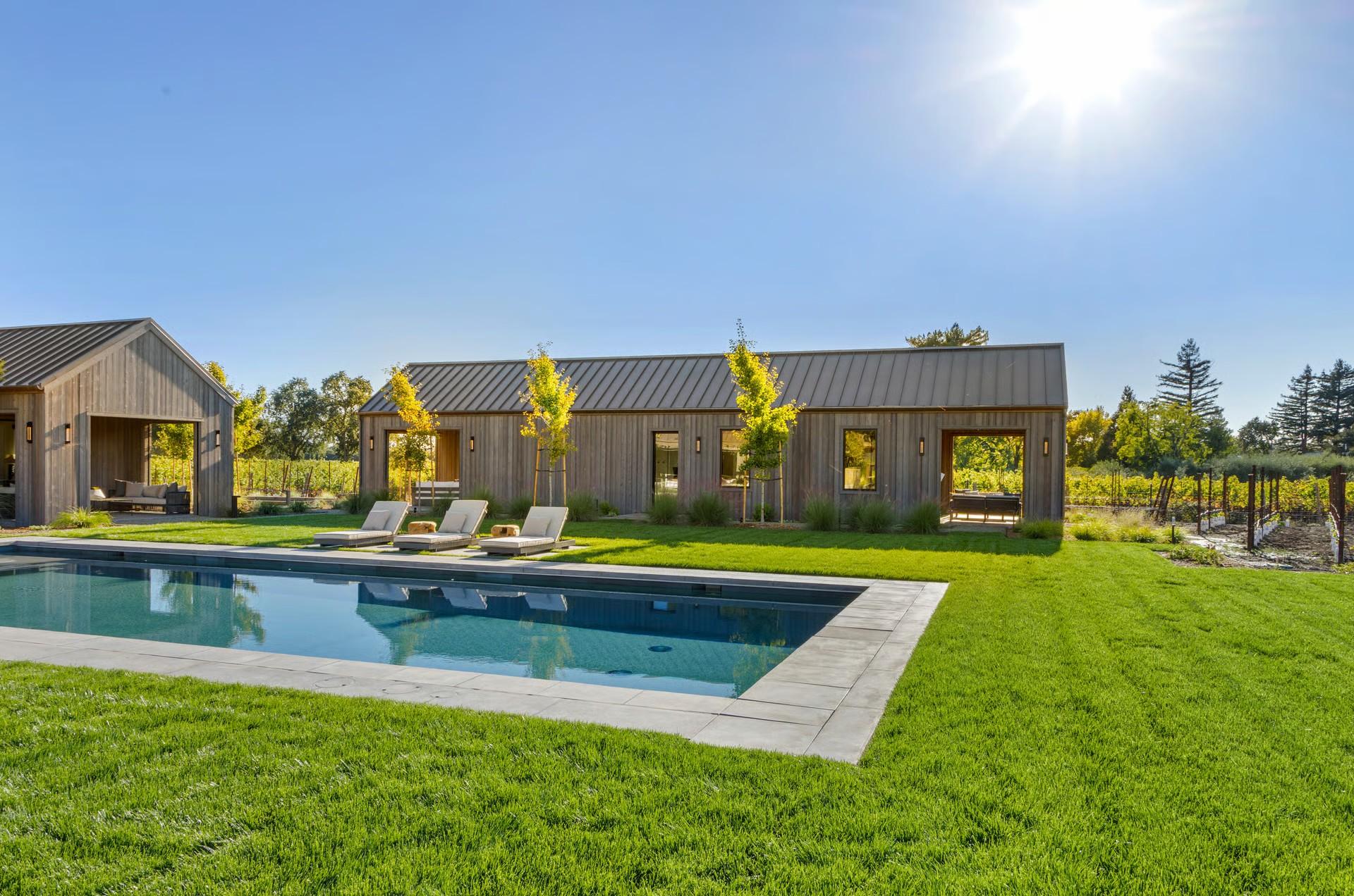 Contemporary single-story home and swimming pool beside vineyard rows