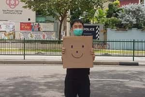 手舉微笑紙板的他  在新加坡遭控非法集會