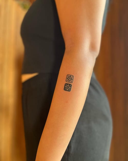 A minimalist blackwork geometric pattern tattoo on the forearm, featuring simple shapes and clean lines — by Dylan Aiello, los angeles