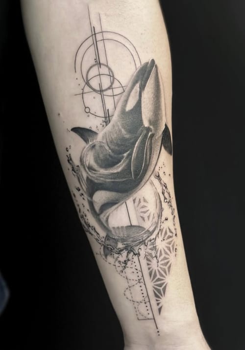 A black and grey realism tattoo of an orca with geometric elements on the forearm, featuring detailed shading and line work — by Jian Liang, los angeles