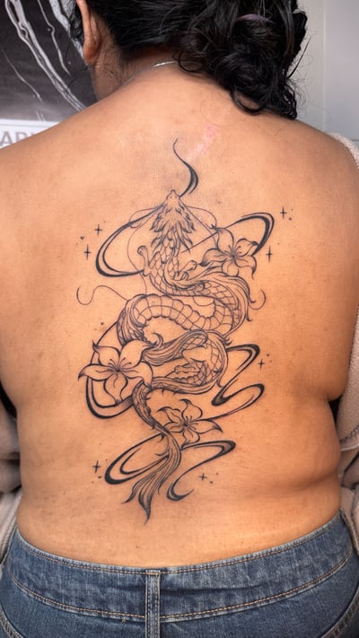 A black and grey linework tattoo of a dragon intertwined with flowers on the back, featuring elegant curves and fine details — by NJ TATTOOZ, los angeles