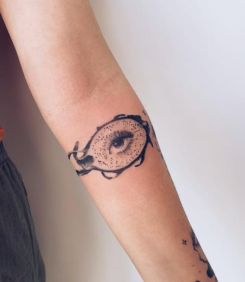 A black and grey surrealistic tattoo of an eye on the forearm, featuring bold blackwork lines and abstract elements — by Level tattoo, los angeles