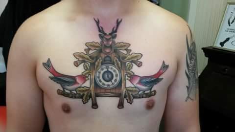 A colorful neo-traditional cuckoo clock tattoo on the chest with birds — by Samuel Connelly, los angeles