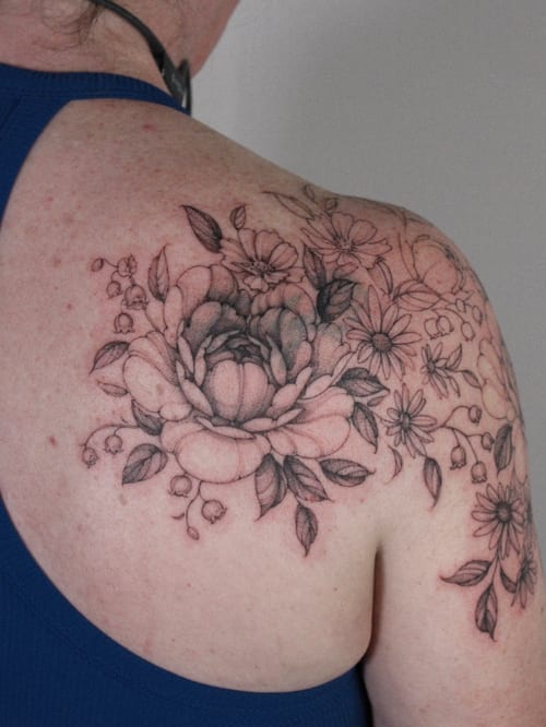 A delicate black and grey floral bouquet tattoo on the shoulder, featuring detailed flowers and leaves — by Melanie Benoit, los angeles