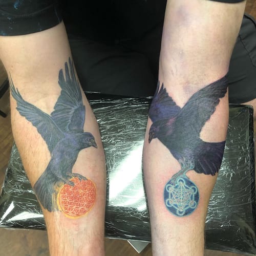 A colorful tattoo of a raven holding a geometric sphere on the forearm, combining realism and sacred geometry — by Sandra Price, los angeles