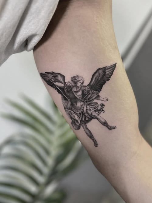 A black and grey realism tattoo of an angel on the inner arm, featuring detailed shading and dynamic pose — by Jian Liang, los angeles