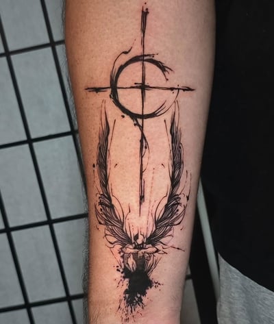 An abstract black and grey cross with wings tattoo on the forearm in a graphic Trash Polka style — by Miguel ANGELO, los angeles