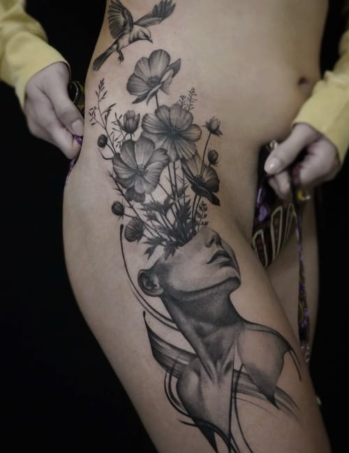 A black and grey surrealism tattoo on the thigh depicting a woman's head with flowers and a bird emerging from it, featuring fine line details and smooth shading — by Jian Liang, los angeles