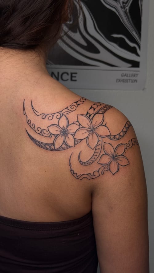 A black and grey Polynesian-inspired tattoo on the shoulder featuring floral patterns and intricate linework — by NJ TATTOOZ, los angeles