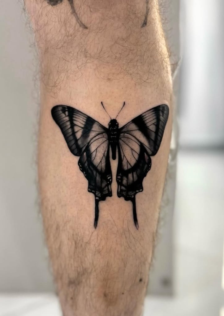 A realistic black and grey butterfly tattoo on the calf with detailed shading and bold outlines — by otaybeatdown, los angeles