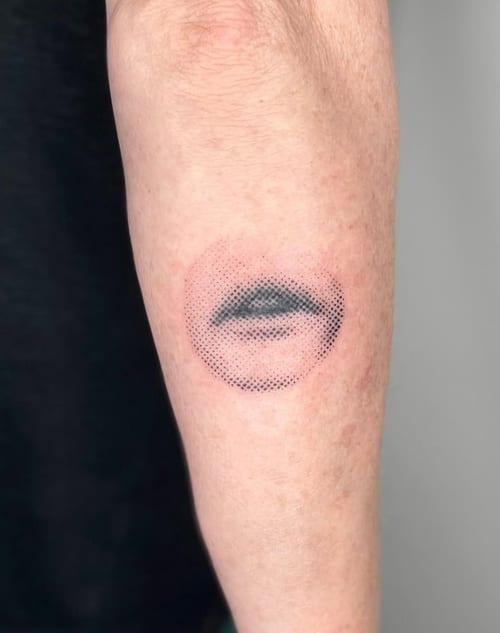 A minimalist dotwork tattoo of a partial face on the forearm, featuring a black and grey color scheme with a focus on the eye and lips — by Level tattoo, los angeles
