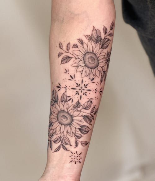 A delicate black and grey fine line sunflower tattoo on the forearm with clean floral details — by Melanie Benoit, los angeles