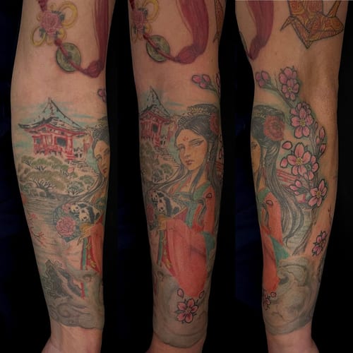 A colorful Japanese-style tattoo on the forearm depicting a woman in traditional attire surrounded by cherry blossoms and a scenic background — by Sandra Price, los angeles