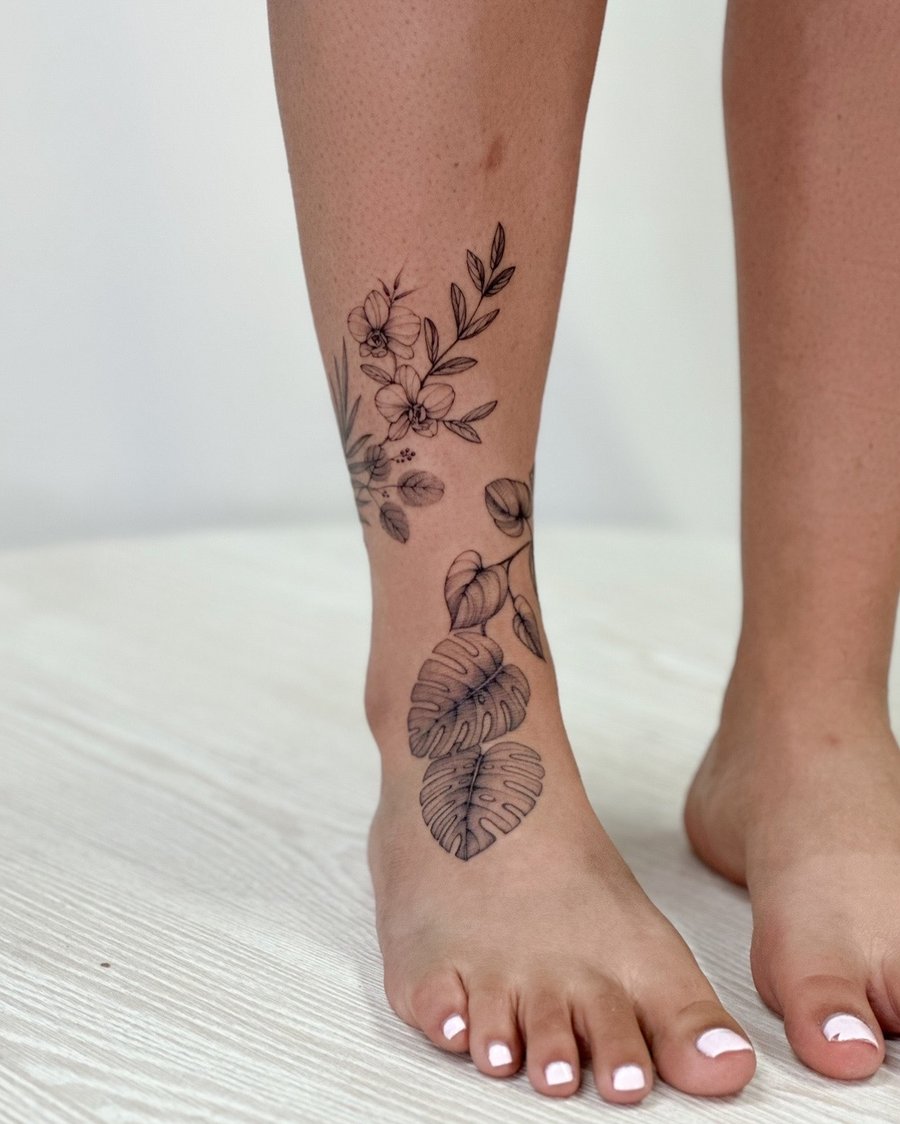 A delicate black and grey fine line tattoo of flowers and leaves on the leg, showcasing a minimalist botanical design — by Melanie Benoit, los angeles