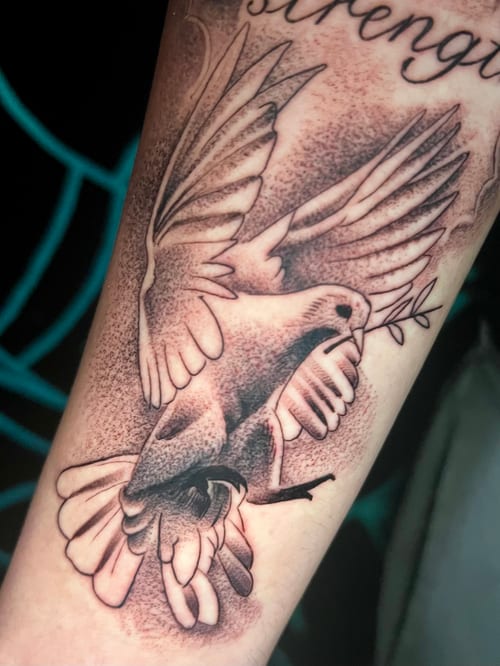 A black and grey dotwork tattoo of a bird holding an olive branch on the forearm, featuring detailed shading and fine lines — by Josue Bravo, los angeles