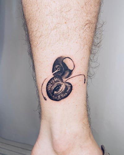 A surreal black and grey tattoo of an eye integrated into an ant design on the calf, featuring bold blackwork style — by Level tattoo, los angeles
